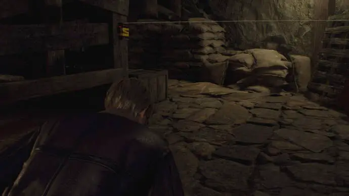 Leon se agacha bajo un cable trampa en el Capítulo 1 de Resident Evil 4 Remake